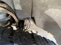 View of the underside of a 2014 GMC Sierra 1500 showing a tire and part of the suspension system with visible components and wiring