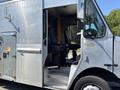 A 2008 Workhorse W62 delivery truck showing a metallic exterior and an open door revealing a simple interior with two black seats and a step ladder