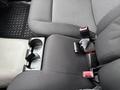 Interior view of a 2011 Chevrolet Colorado showing the front seat with gray fabric upholstery and seatbelt buckles visible next to a cup holder