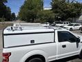 A 2019 Ford F-150 in white with a truck cap and roof rack visible on the top