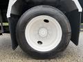 A close-up view of a black tire mounted on a white wheel featuring a silver hub with multiple lug nut openings
