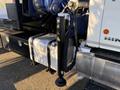 Close-up of a Hino 358 truck's hydraulic jack with a shiny black cylinder and safety markings, connected to a flatbed chassis with a silver fuel tank visible