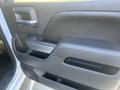 The interior door panel of a 2015 Chevrolet Silverado 1500 featuring a black armrest with a silver accent and various controls for windows and locks