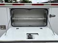 A 2013 Ford F-250 SD with an open compartment showing a metal shelf and a mechanism at the bottom of the area