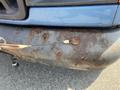A blue 2005 Ford Econoline with visible rust and corrosion on the bumper and surface areas