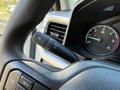 The steering wheel of a 2024 Ford F-550 with control levers for wipers and turn signals visible in the foreground and a speedometer in the background