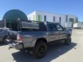 A gray 2010 Toyota Tacoma with a truck bed cover and ladder rack parked with its rear facing the viewer