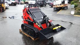 A compact 2023 AGT Industrial tracked loader with a black bucket and red chassis positioned on a wooden pallet