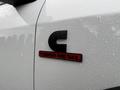 A close-up of a black and red Turbo Diesel badge on a white 2024 RAM 5500 truck with raindrops on the surface