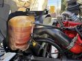 An engine compartment featuring a 2017 International 4300 coolant reservoir with a black hose connecting to the engine and visible red engine components