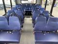 Interior view of a 2020 Chevrolet Express with blue fabric seats arranged in rows and a central aisle leading to a driver's seat at the front