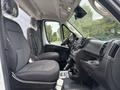 The interior of a 2023 RAM Promaster 3500 featuring two front seats with gray upholstery and a dashboard with controls and storage compartments