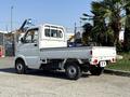 A white 2008 Suzuki Carry mini truck with a flatbed design and a compact cab is parked with its rear facing the viewer