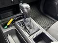 Gear shifter of a 2016 Toyota Tacoma with a leather boot and surrounding console features including storage compartments and controls