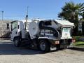 A 2016 Isuzu NPR street cleaning truck with a large suction unit and broom attachment on the front side