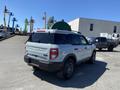 A 2023 Ford Bronco Sport in a light gray color with a roof rack and black wheels parked on a lot