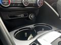 Interior view of a 2023 Alfa Romeo Giulia showing the gear shift and cup holders with a carbon fiber finish