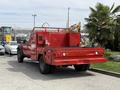A red 2013 Ford F-550 with a flatbed and utility body is parked, showcasing its rear view and equipment mounted on the bed