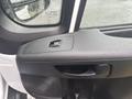 The interior door handle of a 2023 RAM Promaster 3500 with a power window control button and textured black surface