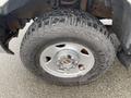 A close-up of a rugged tire mounted on a silver alloy wheel from a 2005 Ford F-350 SD showcasing deep treads designed for off-road driving
