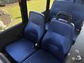 Blue upholstered seats in a Chevrolet Express van with seat belts visible and a simple design featuring a smooth surface and ergonomic backrests