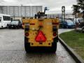 A yellow 2015 Camoplast SW 4S snowplow viewed from the rear with a triangular red warning sign and various lights and markings on the back