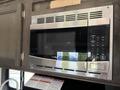 A built-in microwave oven with a stainless steel finish and a digital control panel featuring numbered buttons and various cooking options