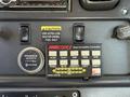 Dashboard controls of a 2010 Freightliner M2 106 featuring buttons for various functions a gauge and a caution label