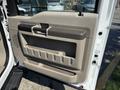 The interior door panel of a 2008 Ford F-550 featuring a beige finish with a built-in handle and storage compartments