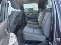Interior view of a 2011 Chevrolet Avalanche showing the back row of seats with a simple cloth design and seat belts visible
