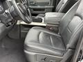 Interior of a 2018 RAM 1500 featuring black leather seats with a central console the driver's seat is visible with prominent stitching and a RAM logo on the headrest