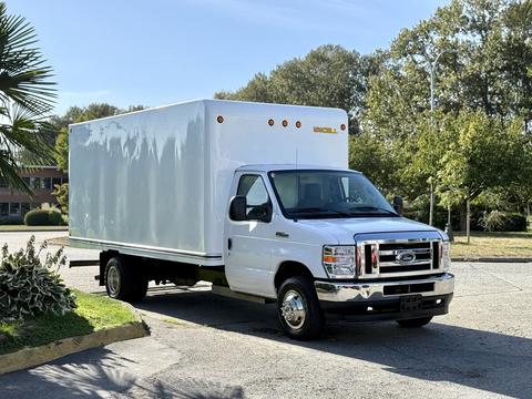 A white 2021 Ford Econoline box truck with a large cargo area and chrome front grille parked in a lot