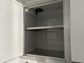 An empty cabinet with two metal shelves inside and a light fixture attached to the top of the interior walls