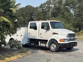 A 2006 Sterling Acterra truck with a white exterior featuring a double cab and side compartments for storage