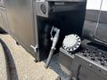 A close-up of a black 2005 GMC C7500 Topkick featuring a valve and a cylindrical cap on the side of the vehicle's body