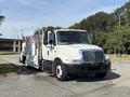 A 2006 International 4300 truck with a white body and gray metal utility bed parked on the street