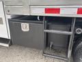A 2014 Ford F-550 featuring a metal toolbox with a latch and a mounted storage tank next to it on the vehicle's side