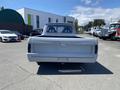 A 1962 Ford 2WHDR truck with a gray exterior viewed from the rear showing the letters F O R D embossed on the tailgate