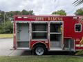 A 2007 Ford F-550 fire rescue truck with open compartments revealing storage space inside
