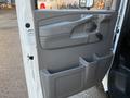 A white 2015 GMC Savana van with a gray interior door panel featuring a handle a control knob and a storage compartment