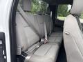 The interior of a 2018 Ford F-150 showing the back seat with gray fabric upholstery and seat belts in place
