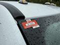 A red and white certificate of approval sticker affixed to the top corner of a white 2020 Ford F-550 with raindrops on the surface
