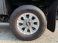 Close-up of a silver alloy wheel of a 2021 Ford F-350 SD featuring a black tire with an aggressive tread pattern