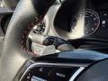 2024 Kia Forte5 interior with a leather-wrapped steering wheel featuring red stitching and various controls on the dashboard including speedometer and multimedia settings