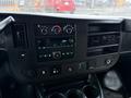 Dashboard of a 2016 GMC Savana featuring audio controls climate knobs and various buttons with a display screen in the center