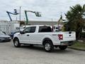A white 2018 Ford F-150 pickup truck with a crew cab and 4x4 badge parked with visible chrome wheels and rear tailgate