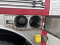 A close-up view of two large metallic exhaust outlets on a fire truck with a yellow valve handle and textured silver paneling