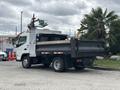 A 2015 Mitsubishi Fuso FE160 truck with a flatbed and a rear gate is parked, featuring a white cab and gray cargo area
