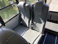 Interior view of two gray bus seats with seat belts in a school bus