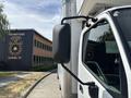 A white 2018 Hino 195 truck with a visible side mirror is parked in front of a building